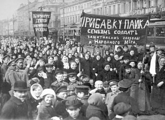 A demonstration of workers from the Putilov plant in Petrograd (modern day St. Peterburg), Russia, during the February Revolution. The left banner reads (misspelt) "Feed [plural imperative] the children of the defenders of the motherland"; the right banner, "Increase payments to the soldiers' families - defenders of freedom and world peace". Both refer to the economic toll the First World War was having on civilian life, February 1917 (probably around March 7 [O.S. February 22]) Photo: Unknown. Public Domain.