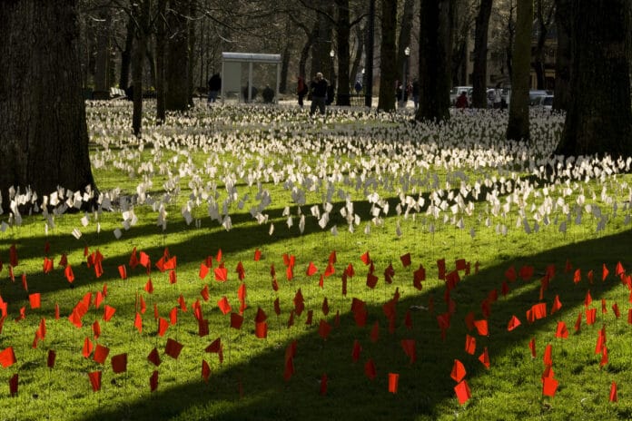The Iraq Body Count Exhibit at Portland State University, Portland, Oregon, USA. Each white flag represents at least 5 Iraqis, and each red flag represents 5 Americans, killed as a result of the 2003 invasion of Iraq. As of March 15, 2008, at least 655,000 Iraqi civilians and 3,972 American soldiers have died. Photo: Lisa Norwood. (CC BY-NC 2.0).