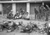 Tet Offensive, Saigon 1968. A Viet Cong prisoner sits next to corpses of 11 of his slain fellow guerrillas after a street fight in Saigon-Cholon on February 11, 1968. In the background are Vietnamese Marines that defeated a Viet Cong platoon holed up in the residential area. The prisoner was later taken out for interrogation. Photo: Eddie Adams/AP. (CC BY 2.0). Source: flickr.com