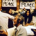 Recording “Give Peace a Chance”. Left to right: Rosemary Leary ( face not visible), Tommy Smothers (with back to camera), John Lennon, Timothy Leary, Yoko Ono, Judy Marcioni and Paul Williams, Date: 1969. Photo: Roy Kerwood – Originally uploaded to English Wikipedia by Roy Kerwood, (CC BY 2.5).