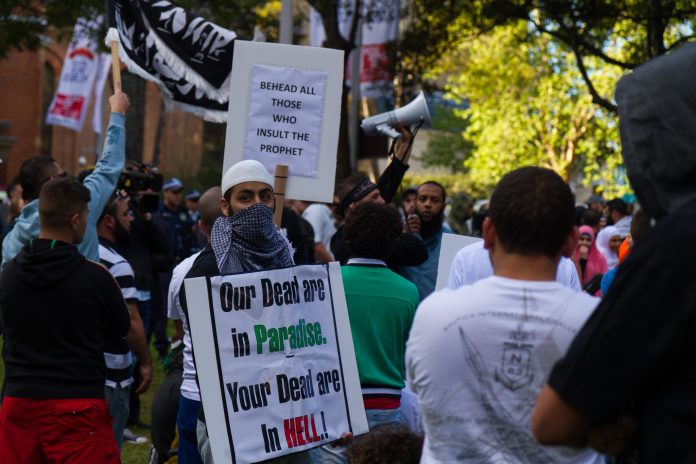 Muslim protesters carry signs reading