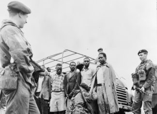 Suspected Mau Mau terrorists being searched by security forces. These suspects had been rounded up in Kanyuki during Operation Scaramouche.