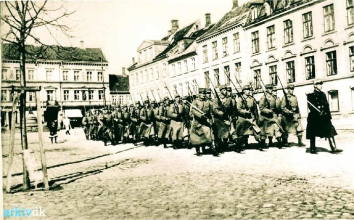 Generalstrejken i 1922. Soldater marcherer med opplantede bajonetter på Frederiksplads. (Isenkram Centret genkendes) Foto: Ukendt / Randers Stadsarkiv.