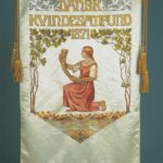 I kvindernes takketog til kongen i 1915 blev Dansk Kvindesamfunds banner båret forrest. Dansk Kvindesamfunds banner brugt ved landsmøderne frem til 1967. Motivet er tegnet af kunstneren Anna E. Munk, 1911.