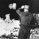 A member of the SA throws confiscated books into the bonfire during the public burning of “un-German” books on the Opernplatz in Berlin. 10 May 1933. Photo: Unknown. Public Domain.