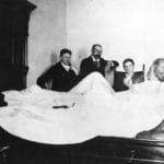 Mark Twain being interviewed by Ernest John Harrison and other reporters from his hotel bed in Vancouver on August 18, 1895. Photo: George Thomas Wadds (1874–1962),  photographer. Public domain.