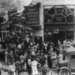 Crowd at New York’s American Union Bank during a bank run early in the Great Depression. The Bank opened in 1917 and went out of business on June 30, 1931. Photo: Unknown. Public Domain.
