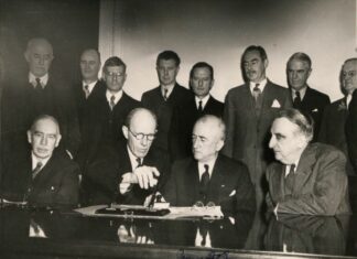 Photograph of the signing of the Anglo-American loan agreement at the State Dept, Washington, on 6 Dec. 1945. Sitted from left to right: John Maynard Keynes, Lord Halifax, James Byrnes, Fred Vinson. Photo: The National Archives UK. Collection: Part of the Colonial Office photographic collection held at The National Archives. Public Domain.