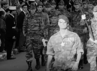 Scene fra filmen, hvor franske faldskærmstropper ankommer med obersten i spidsen, hyldet af folk fra den franske koloni i Algeriet. Skærmbillede fra filmen.