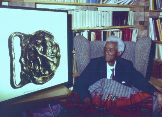 C.L.R. James viewing an enlargement of the Barbados Cricket Buckle at his home in Brixton, London. 1988. Foto: Hill123.