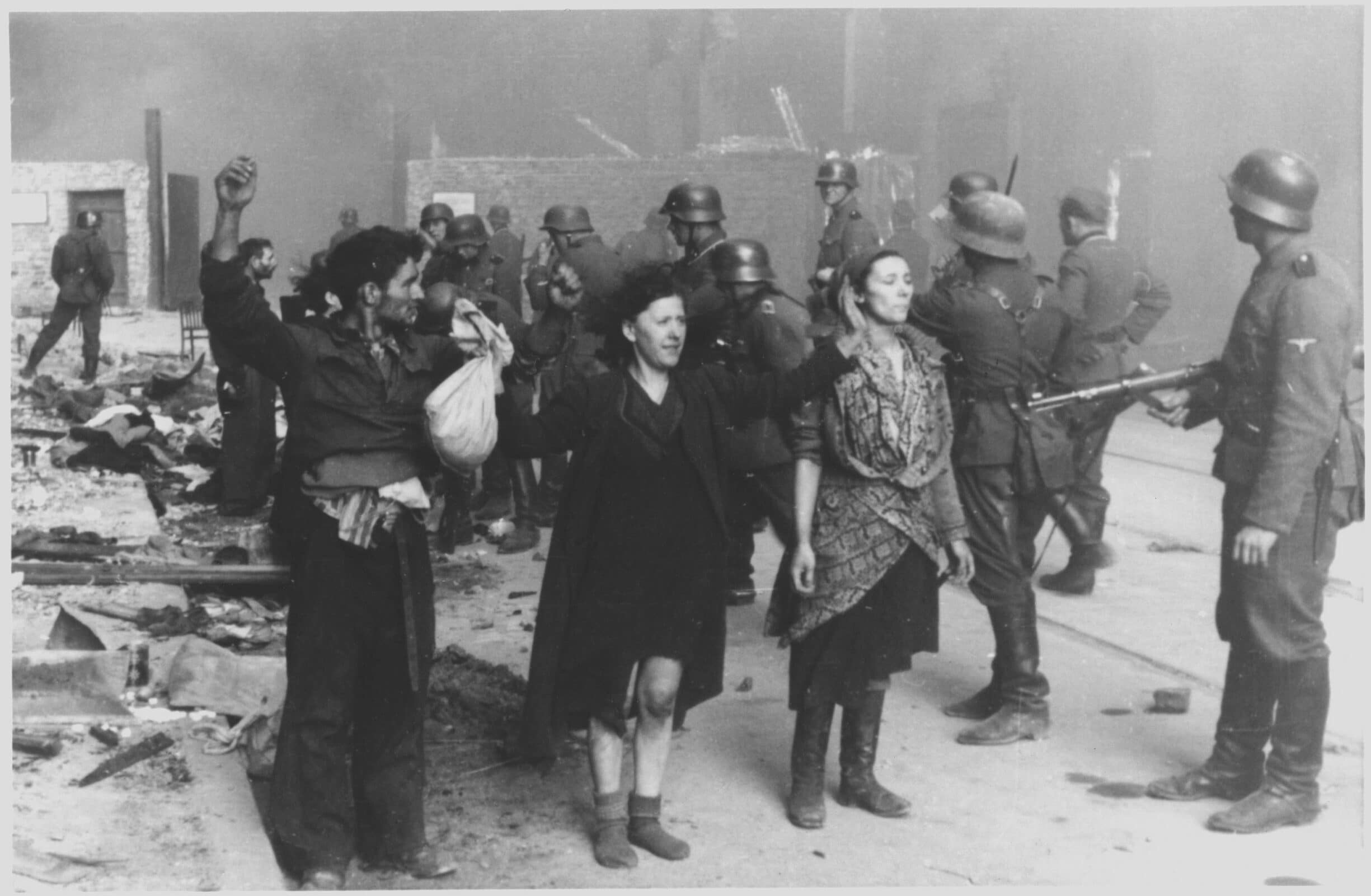 The original caption of the Nazi: "These bandits offered armed resistance". Picture taken at Nowolipie street looking East, near intersection with Smocza street. In the back one can see ghetto wall with a gate, between 19 April 1943 and 16 May 1943. Photo: Unknown author (Franz Konrad confessed to taking some of the photographs, the rest was probably taken by photographers from Propaganda Kompanie nr 689. Collection: Bildarchiv Preussischer Kulturbesitz (BPK). Public Domain.