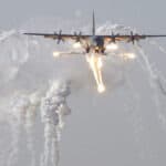 A British C-130J Hercules aircraft launches defensive countermeasures prior to being the first coalition aircraft to land on the newly reopened military runway at Baghdad International Airport, 1 July 2003. Photo: Master Sergeant Robert R. Hargreaves Jr. Public Domain.