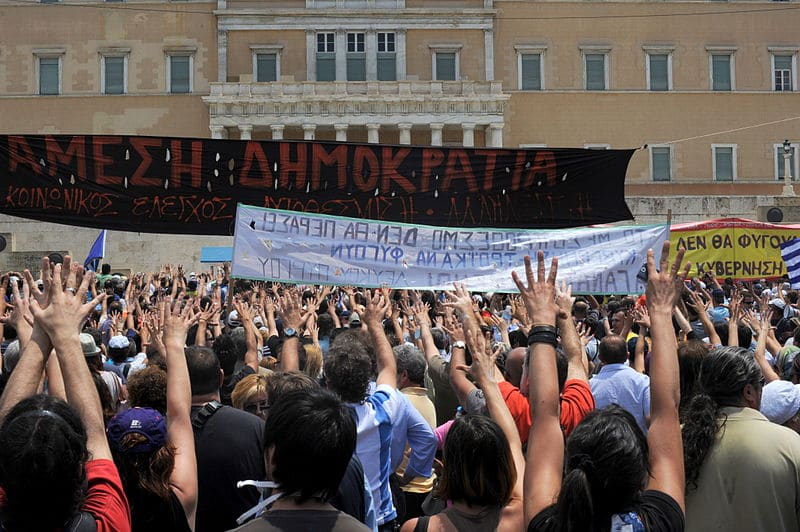 Demonstrations in front of the Greek parliament - Moutza against the parliament (29 June 2011) The most traditional gesture of insult among Greeks: it consists of extending all fingers of one or both hands and presenting the palm or palms towards the person to be insulted in a forward motion. Photo: Ggia (CC BY-SA 3.0) Source: https://commons.wikimedia.org/wiki/File:20110629_Moutza_demonstrations_Greek_parliament_Athens_Greece.jpg