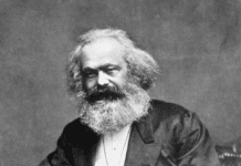 Photographic portrait of Karl Marx seated with a thumb in his lapel and his hand on his thigh, 1875. From: Reminiscences of Carl Schurz, Vol. I, New York: McClure Publ. Co., 1907, Chap. 4, facing p. 170. (This is the source of the first version only. Photo: John Jabez Edwin Mayal (1813–1901). Public Domain.