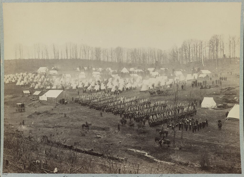 Camp of 36th Pennsylvania Infantry. Military band, troops on the field, officers on horseback, and tents in the background. Photo: Taken between 1861 and 1865. Collection: Civil War Photograph. the United States Library of Congress's Prints and Photographs division. Public Domain.
