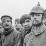 Der Weihnachtsfriede von 1914. “British and German soldiers fraternising at Ploegsteert, Belgium, on Christmas Day 1914, Front of 11th Brigade, 4th Division. Possibly Riflemen Andrew (middle) and Grigg (second from the right, background) of the London Rifle Brigade with troops of the 104th and 106th Saxon Regiments..” Photo: Robin’s Sackhaare. Public Domain.